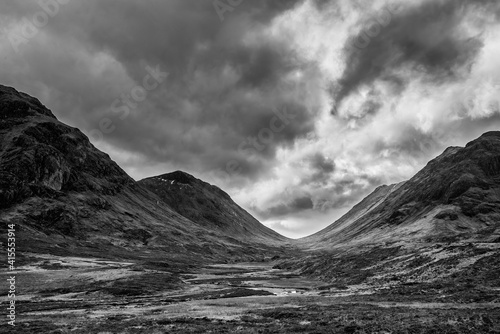 Majestic black and white landscape image view down Glencoe Valley in Scottish Highlands with mountain ranges in dramatic Winter lighting
