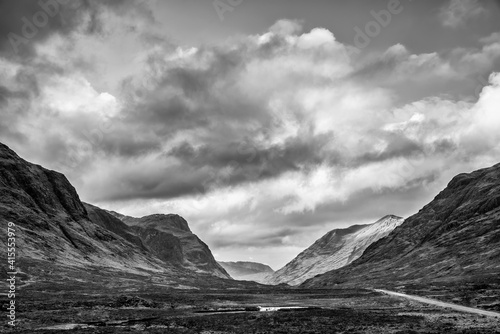 Majestic black and white landscape image view down Glencoe Valley in Scottish Highlands with mountain ranges in dramatic Winter lighting
