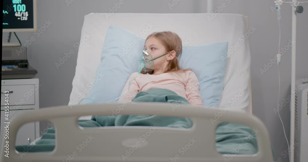 Girl suffering from pneumonia lying in a hospital bed with oxygen mask