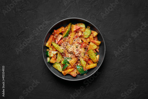 Penang Rojak in black bowl on dark slate table top. Malaysian or indonesian cuisine fruits and vegetables salad dish. Asian Food. Top view