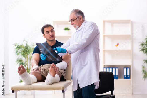 Young injured man visiting old doctor traumatologist