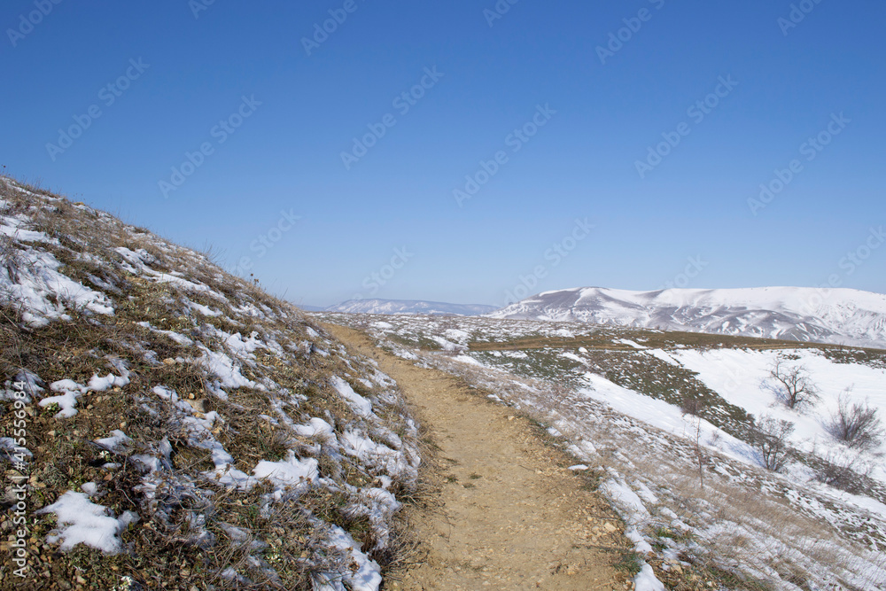 View of the path on the background of the winter mountain landscape and the blue sky in the Crimea.