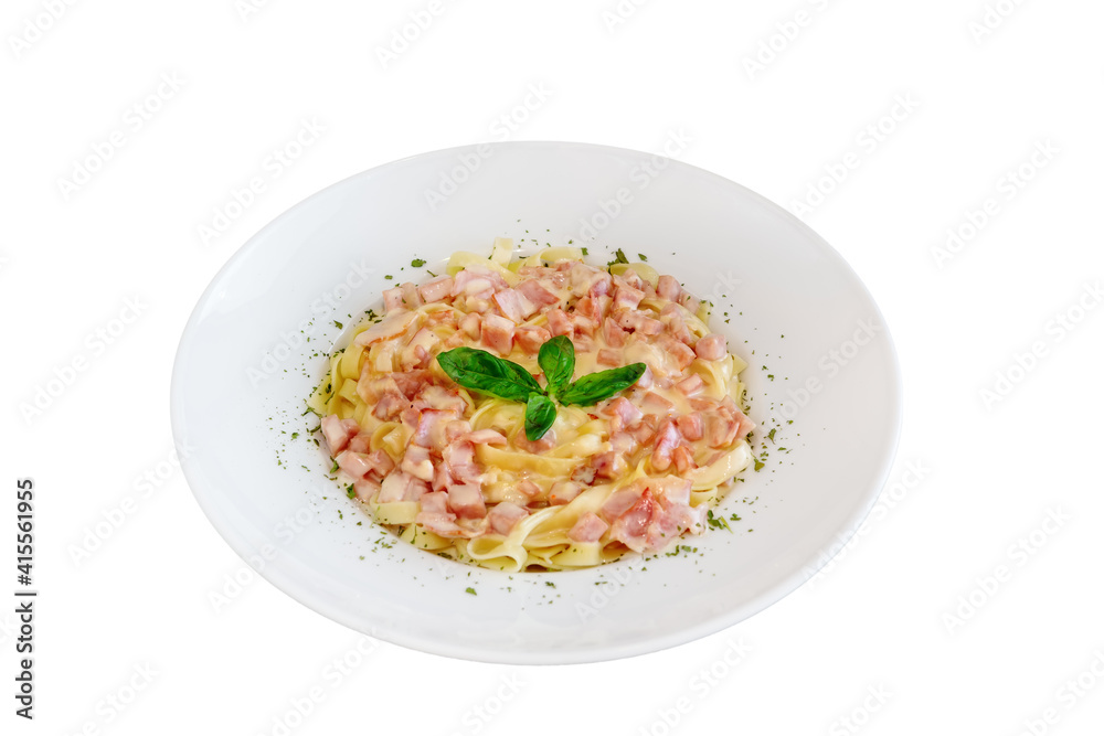 Isolated plate of pasta carbonara made of tagliatelle, bacon, parmesan cheese topped with leaves of basil.