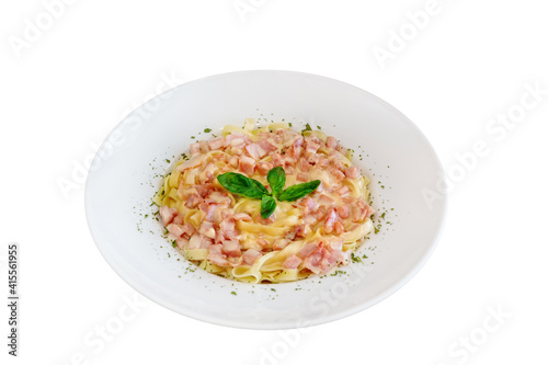 Isolated plate of pasta carbonara made of tagliatelle, bacon, parmesan cheese topped with leaves of basil.