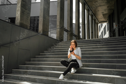 Young woman sitting on stairs with smartphone