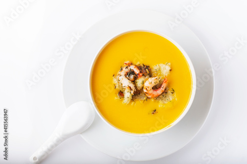 Diet pumpkin soup with shrimp, crouton, turmeric and greens. Healthy food. White background.