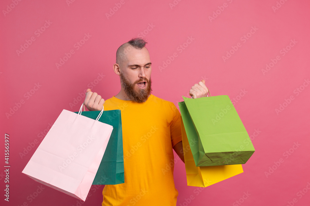 Happy bearded positive man casual look with colorful shopping bags studio pink background Happy bearded positive man casual look with colorful shopping bags studio pink background