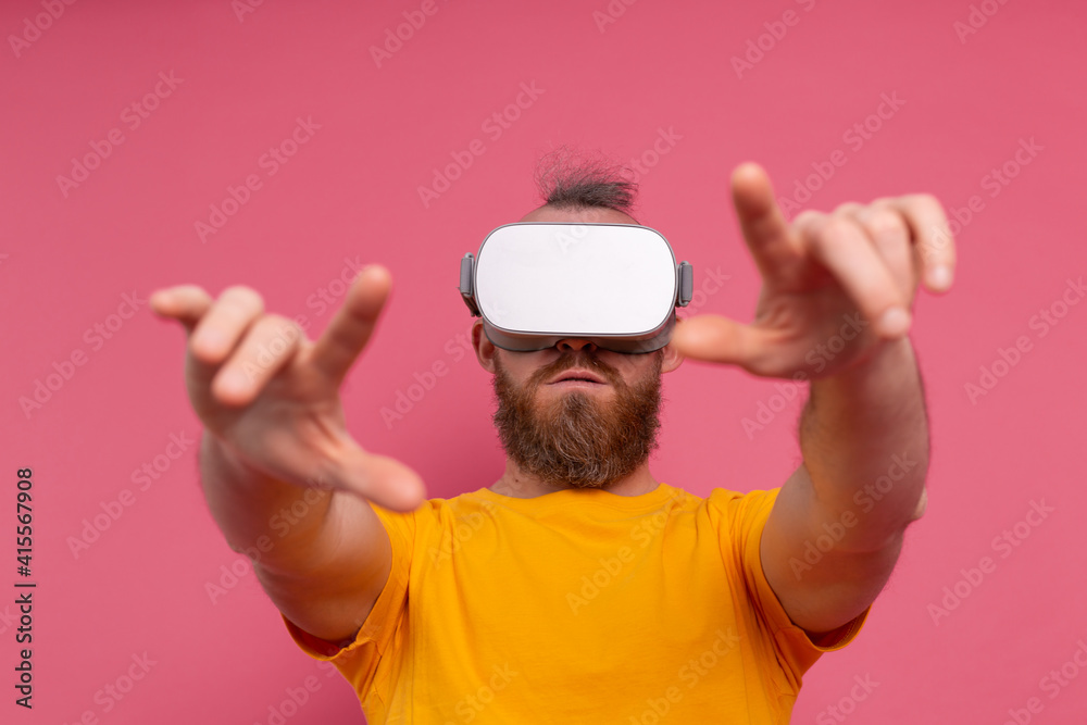 Handsome positive bearded man touching air in vr glasses studio background Handsome positive bearded man touching air in vr glasses studio background