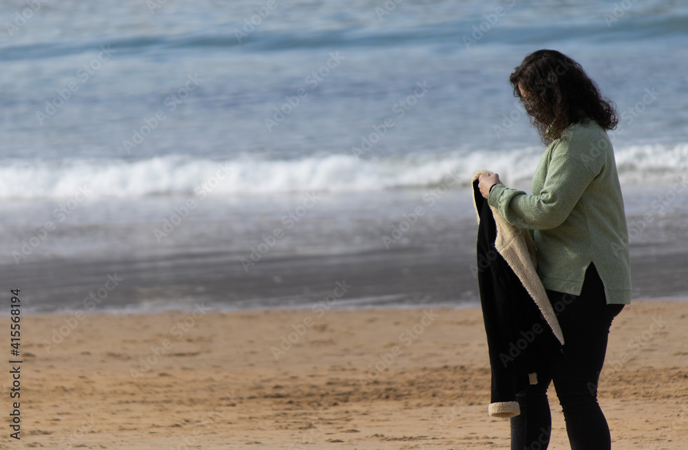 a person walking on the beach holding a jacket a person walking on the beach holding a jacket
