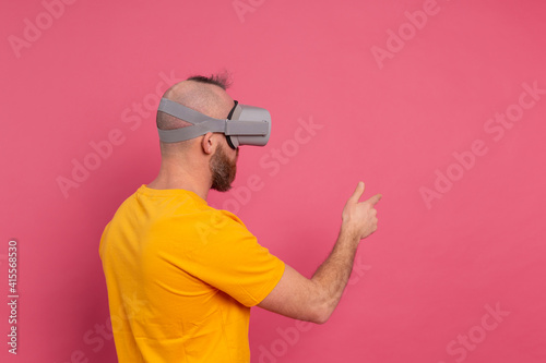 Handsome casual wear men in vr glasses side view pointing to the left text space
