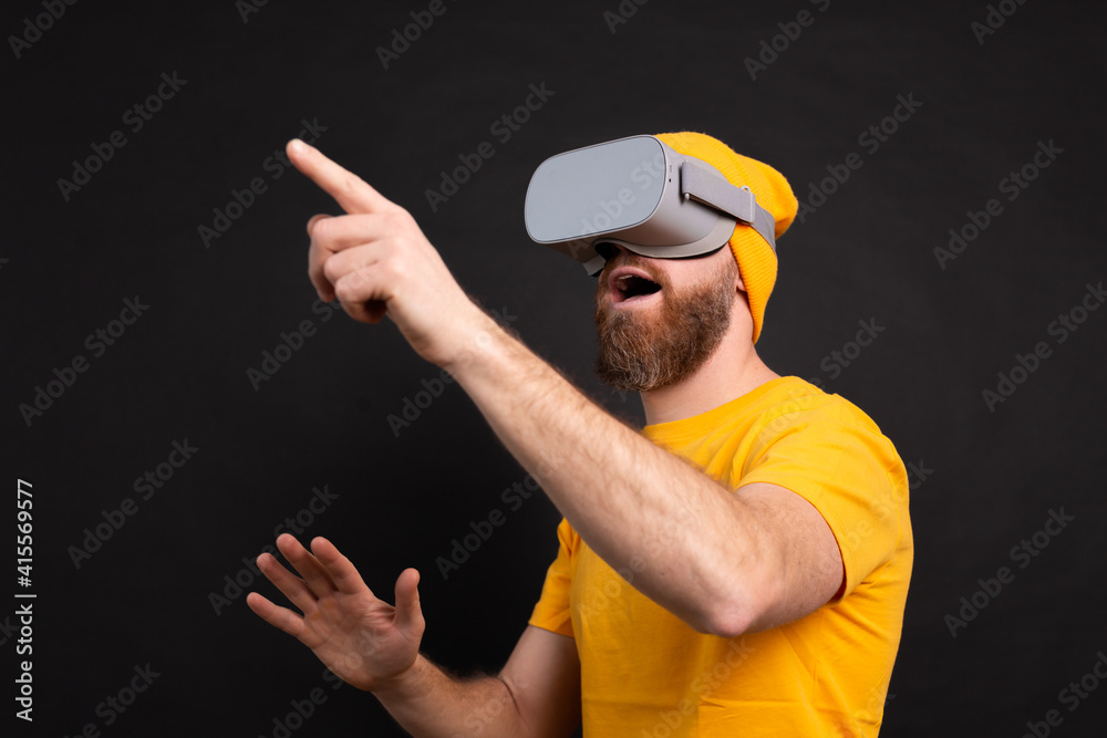 Handsome positive bearded man touching air in vr glasses studio background Handsome positive bearded man touching air in vr glasses studio background