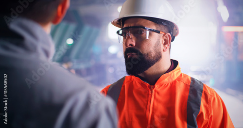 Bearded inspector speaking with worker on factory © Framestock