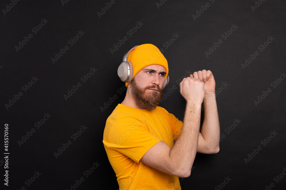 Handsome man in casual dancing with headphones isolated on black background