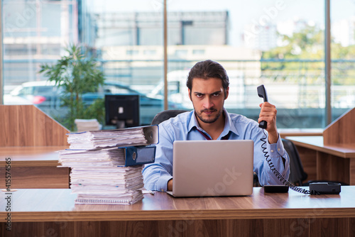 Young male employee unhappy with excessive work in the office