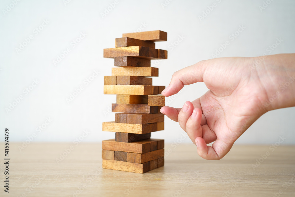 The risk will happen.Hand of engineer playing a blocks wood game on wood table vintage tone. architectural project .as background business concept with copy space. The risk will happen.Hand of engineer playing a blocks wood game on wood table vintage tone. architectural project .as background business concept with copy space.