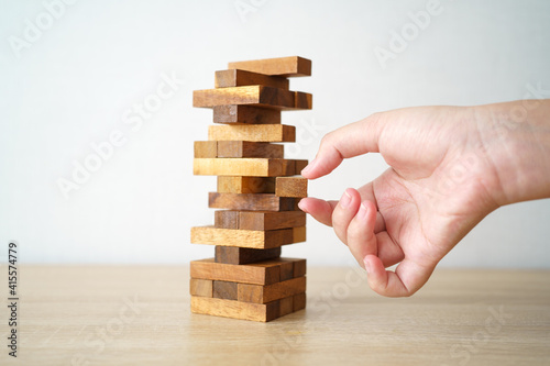 The risk will happen.Hand of engineer playing a blocks wood game on wood table vintage tone. architectural project .as background business concept with copy space.