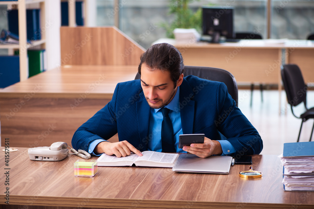 Young male employee reading book in the office Young male employee reading book in the office