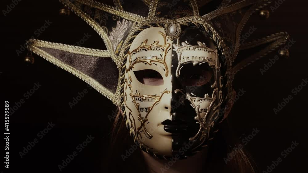 Tempting, sexy woman in mask looking at the camera. Confident, mysterious girl. Dark, theatrical, stylish place. Elegant desire.