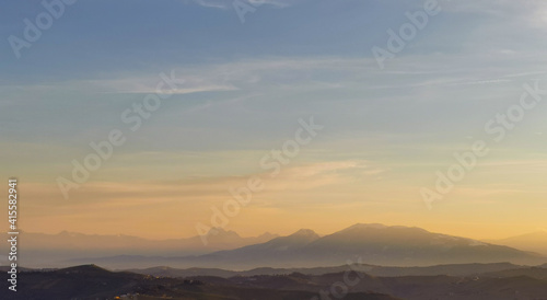 Montagne e valli dell’Appennino in un tramonto di luce e foschia azzurro e arancio © GjGj