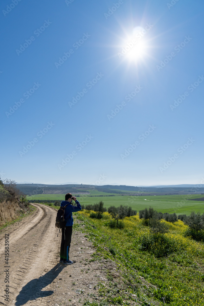 Unrecognized young boy wearing sports clothes and backpack walking in the countryside.