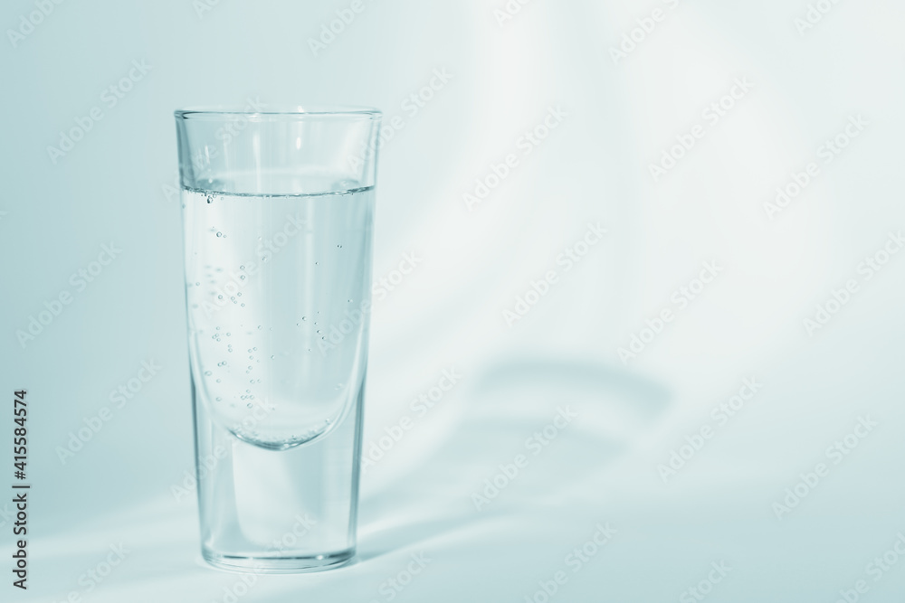 Glass of clean mineral sparkling water on a light blue background Glass of clean mineral sparkling water on a light blue background
