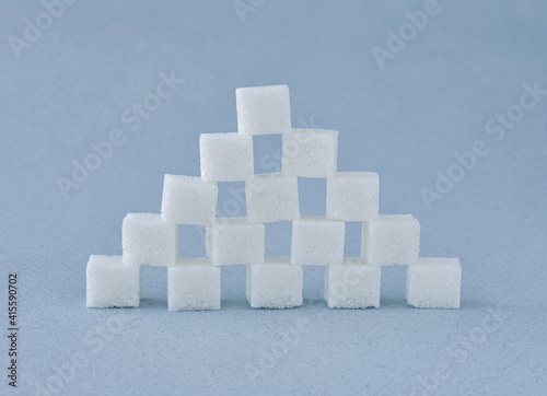A pyramid of refined white sugar cubes on a blue background.
