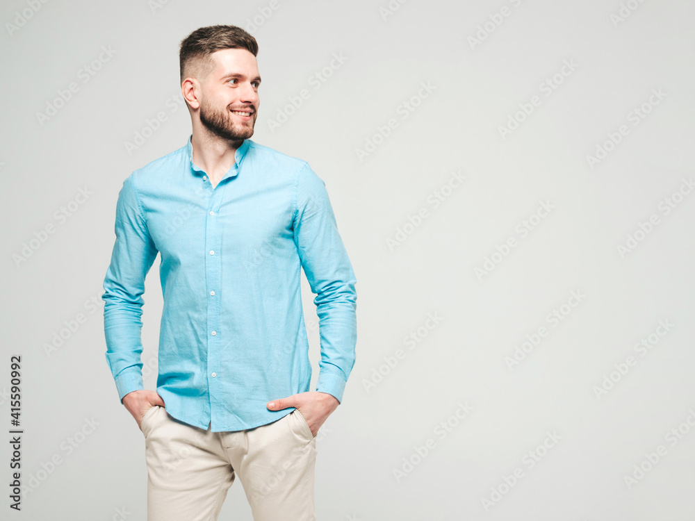 Fototapeta premium Portrait of handsome smiling hipster lumbersexual businessman model wearing casual shirt and trousers. Fashion stylish man posing against grey background in studio