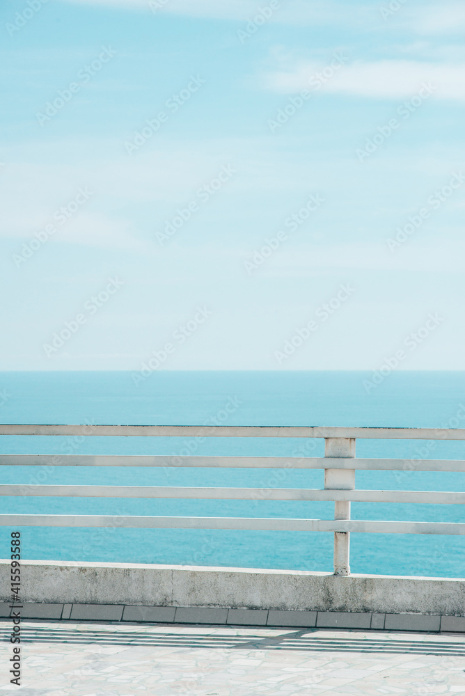 old rusty iron and wooden white fence with sea and sky views, vertical lifestyle stock photo image background