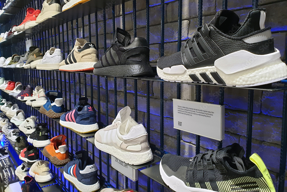 Foto Stock Close up Adidas shoes on store shelf in ICONSIAM Mall, Bangkok.  Adidas is a German corporation that designs footwear and clothing. BANGKOK,  THAILAND - APR 5, 2019. | Adobe Stock