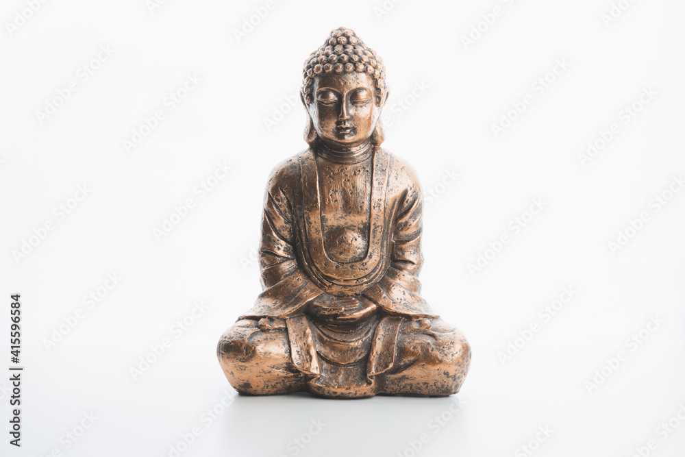 A bronze buddha indoor souvenir statue in lotus position isolated on a plain white background and surface. A bronze buddha indoor souvenir statue in lotus position isolated on a plain white background and surface.