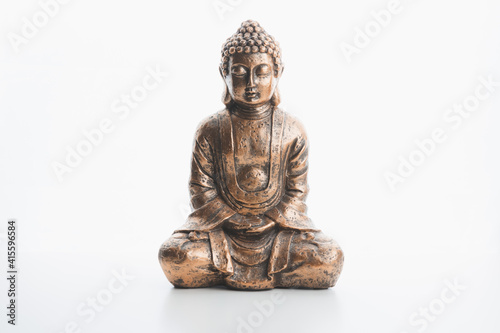 A bronze buddha indoor souvenir statue in lotus position isolated on a plain white background and surface.