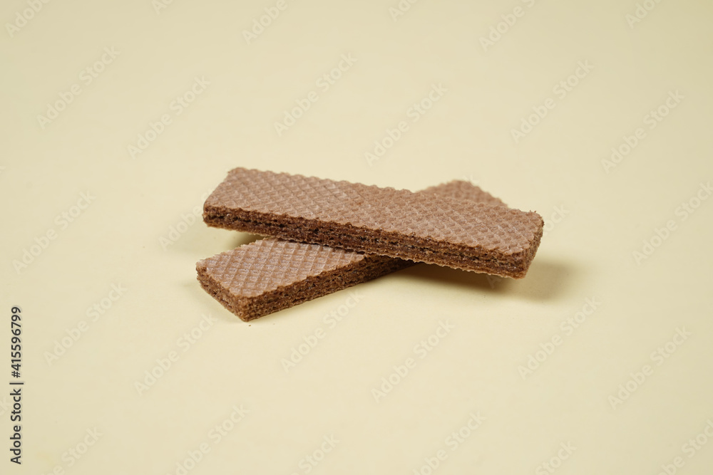 Random pile of wafers isolated on a yellow background. Chocolate biscuit wafers filled with delicious creamy chocolate. Dry and crispy wafers ready to eat. Ready to start the day with a wafer. Random pile of wafers isolated on a yellow background. Chocolate biscuit wafers filled with delicious creamy chocolate. Dry and crispy wafers ready to eat. Ready to start the day with a wafer.
