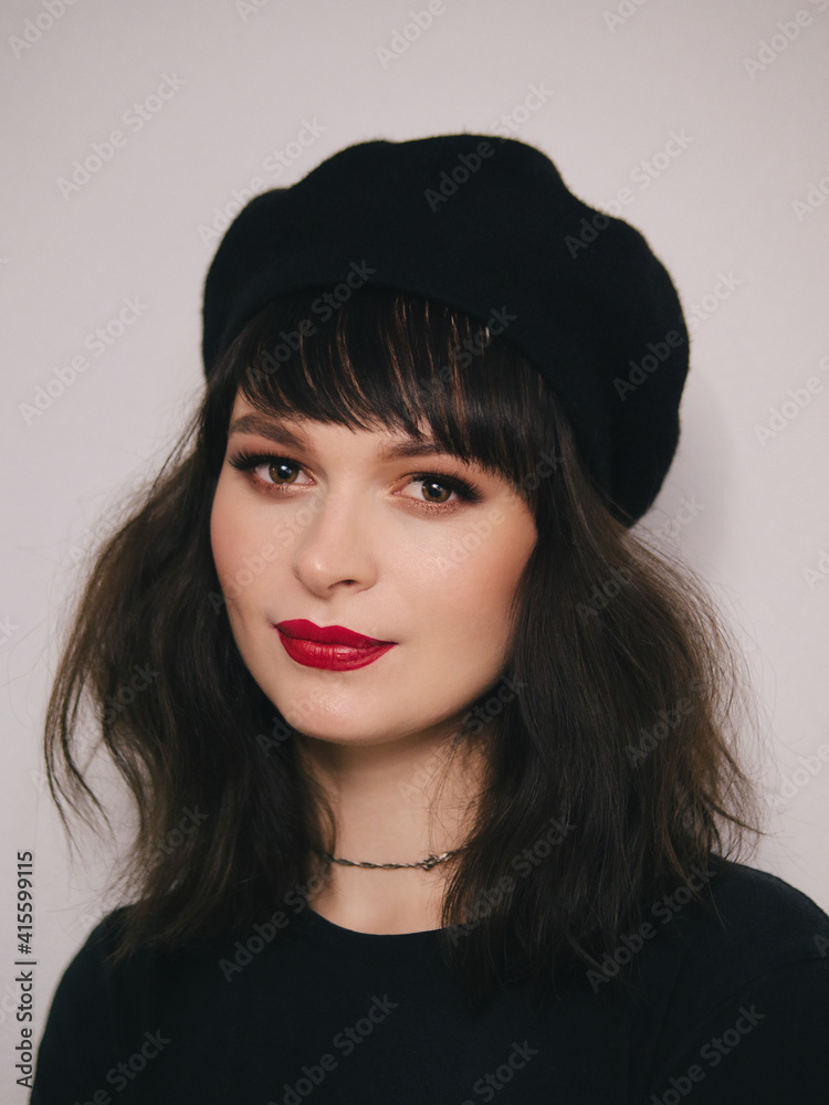 Indoor close up portrait of young beautiful fashionable woman red lips wearing black beret and t-shirt french inspired fashion concept Indoor close up portrait of young beautiful fashionable woman red lips wearing black beret and t-shirt french inspired fashion concept