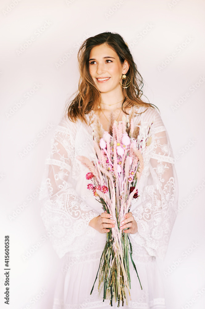 Fashion portrait of pretty young woman wearing boho style dress, holding bouquet of dry flowers, hippie style model posing on white background Fashion portrait of pretty young woman wearing boho style dress, holding bouquet of dry flowers, hippie style model posing on white background