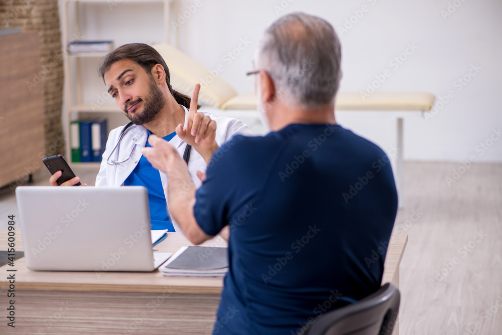 Obraz premium Old male patient visiting young male doctor