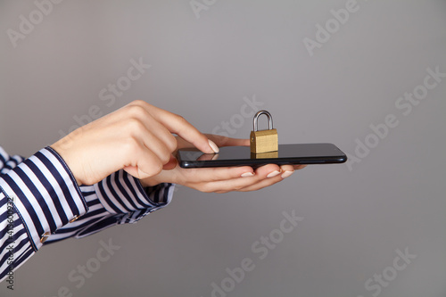 Caucasian woman holds a padlock and phone in her hand.