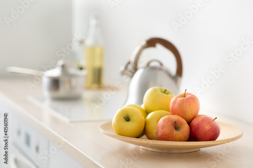 Fruits in plate on table, kettle on stove in modern kitchen, breakfast in morning, healthy food and vitamins