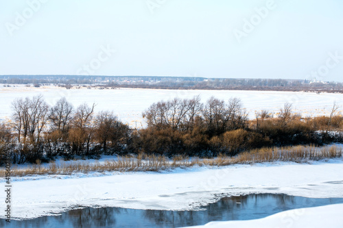 Melting ice on the lake during a winter day. There are trees on the coastline. Winter period. Fantastic winter view