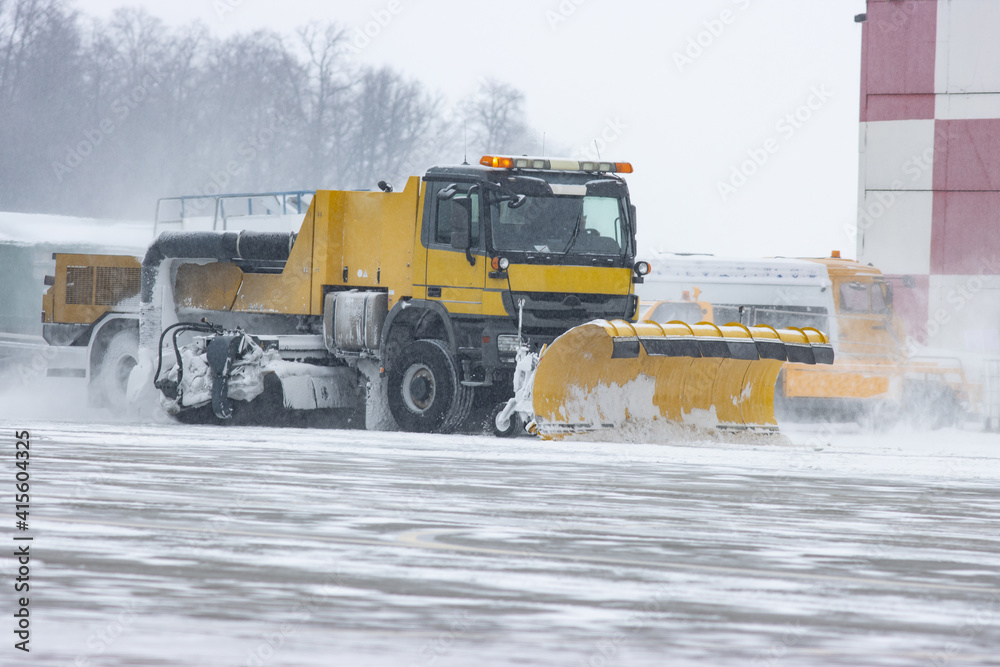 Snowy winter at the airport and snowplow removes snow from the runway Snowy winter at the airport and snowplow removes snow from the runway