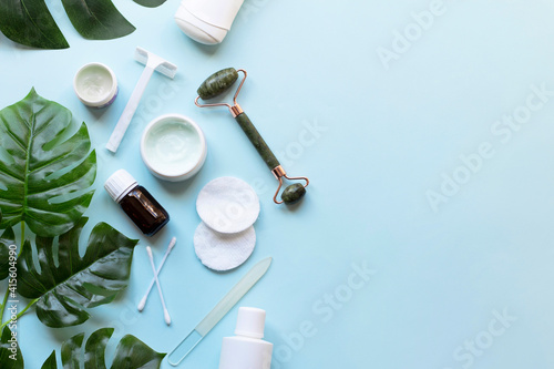 Skin care products. Natural cosmetics, face massage roller, moisturizer face cream on blue background. Skin care concept. Top view 