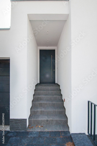 Moderner, eleganter Hauseingang mit Treppen und dunkler Eingangstür