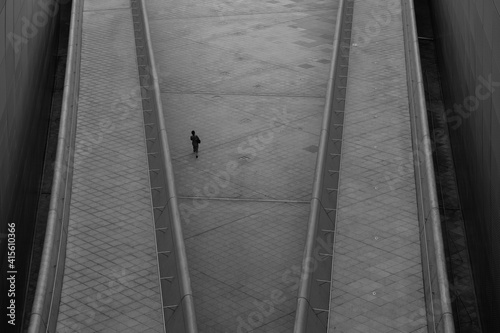 Overhead view of woman walking alone in futuristic looking area in a city.