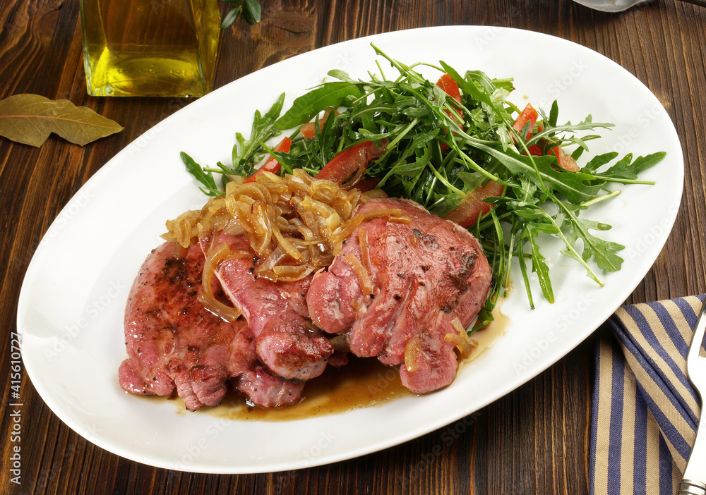 Boiled Veal Tongue Meat Slices with roasted Onions and Salad on wooden Background Boiled Veal Tongue Meat Slices with roasted Onions and Salad on wooden Background