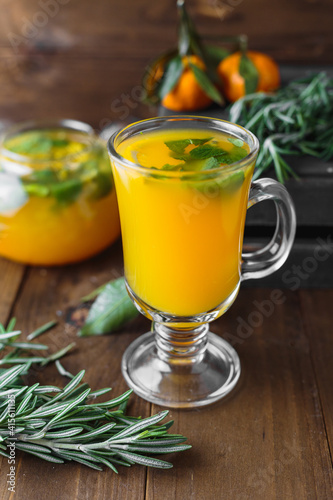 Hot tea with passionfruit and mint in a glass, rosemary and miniature tangerines on the table, selective focus, rustic background, top view 