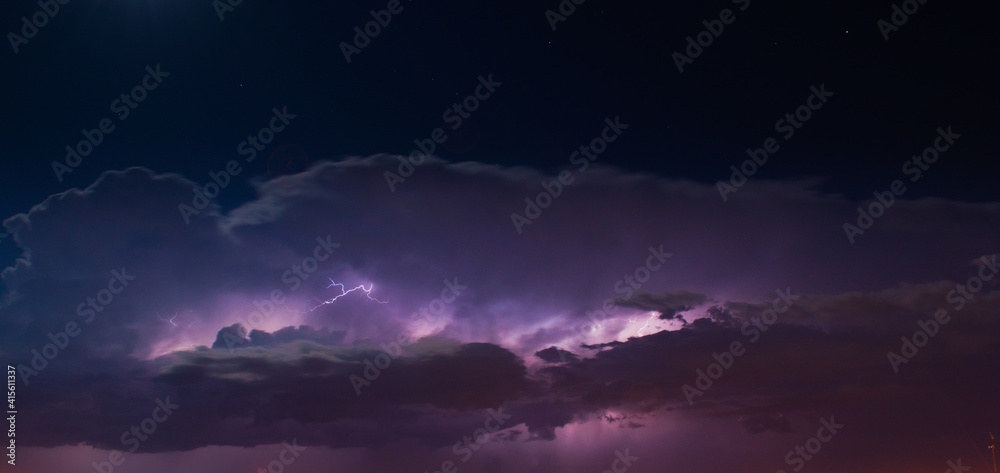 Lightnings in heavy, purple storm clouds at night.