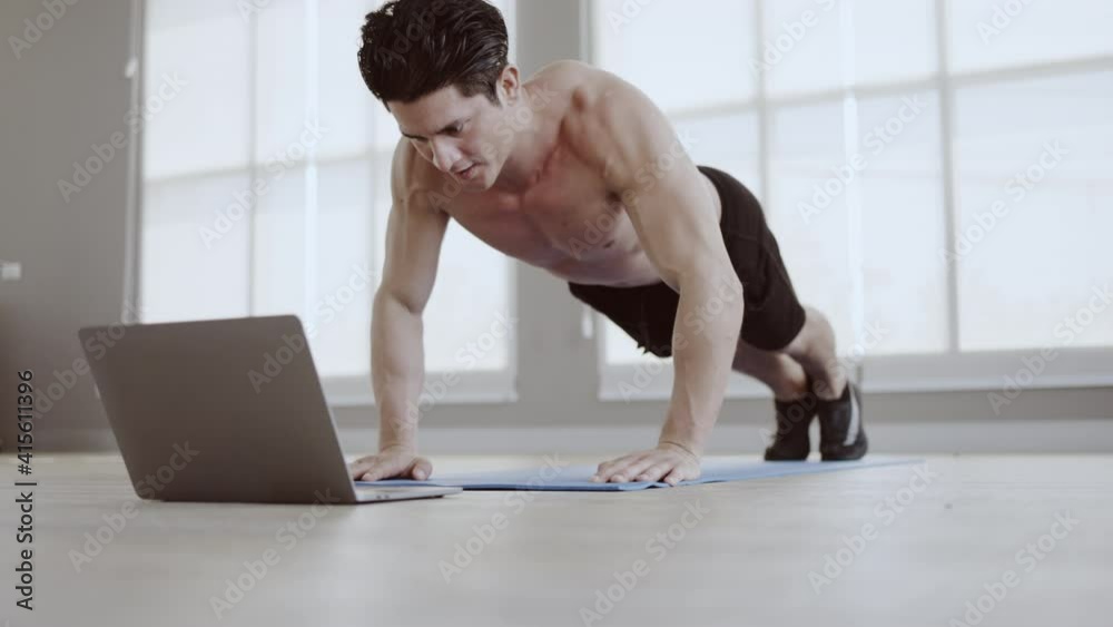Man athletic trainer doing push up in gym And live teaching via laptop Or video call. Exercise strengthens the muscle. Workout take care of your health be in good shape. Distance teaching technology Man athletic trainer doing push up in gym And live teaching via laptop Or video call. Exercise strengthens the muscle. Workout take care of your health be in good shape. Distance teaching technology