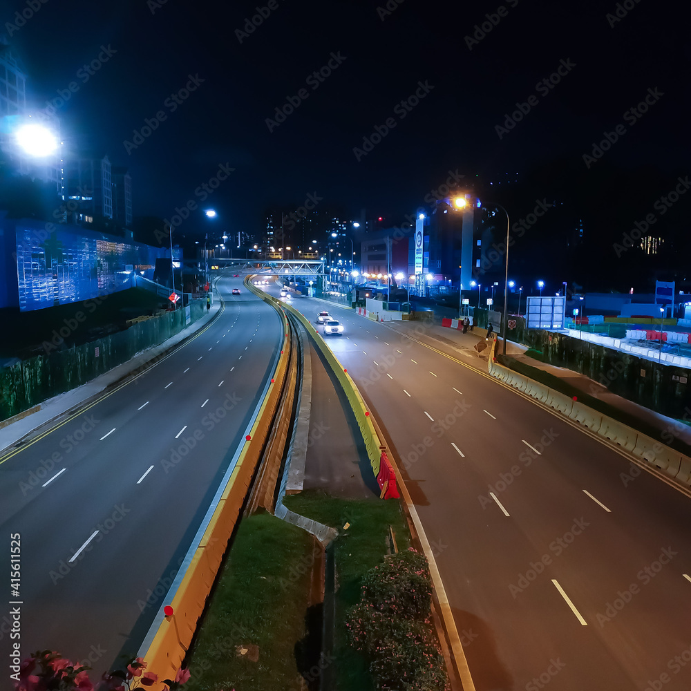 An almost empty well-lit road early in the evening An almost empty well-lit road early in the evening