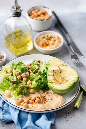 Salad bowl with chickpea hummus, greens and avocado. Healthy vegan salad served with olive oil