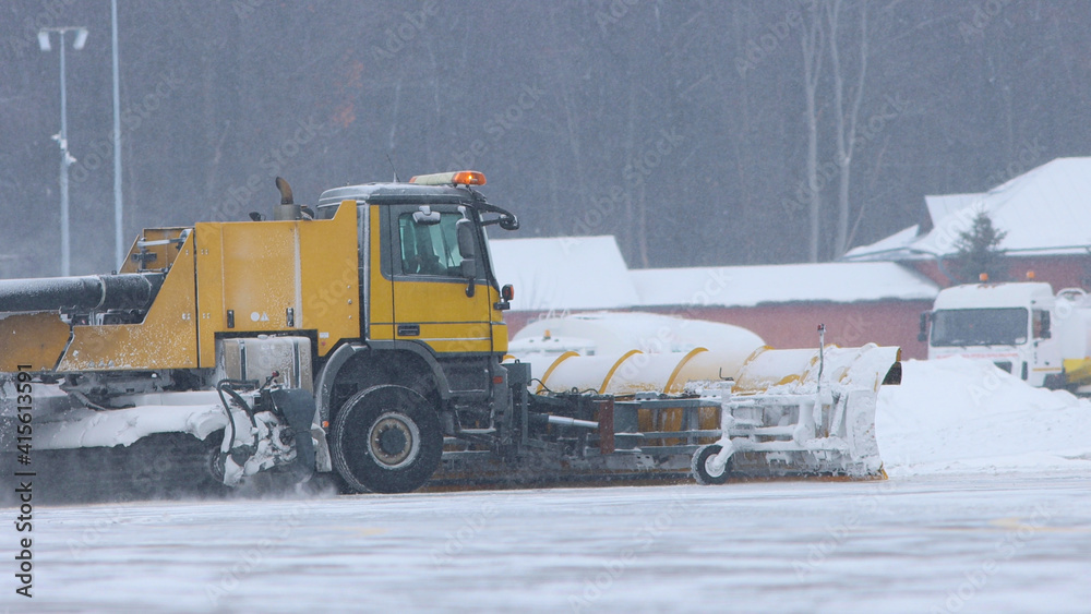 Snowy winter - a big snowplow removes snow from the path on the way Snowy winter - a big snowplow removes snow from the path on the way