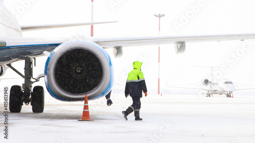 Fotografija A turbine of an airplane on the airfield and a working person in winter time